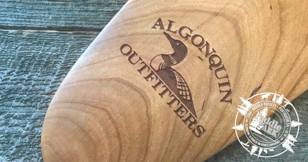 Algonquin Outfitters logo laser engraved on the tip of a cherry Badger canoe paddle