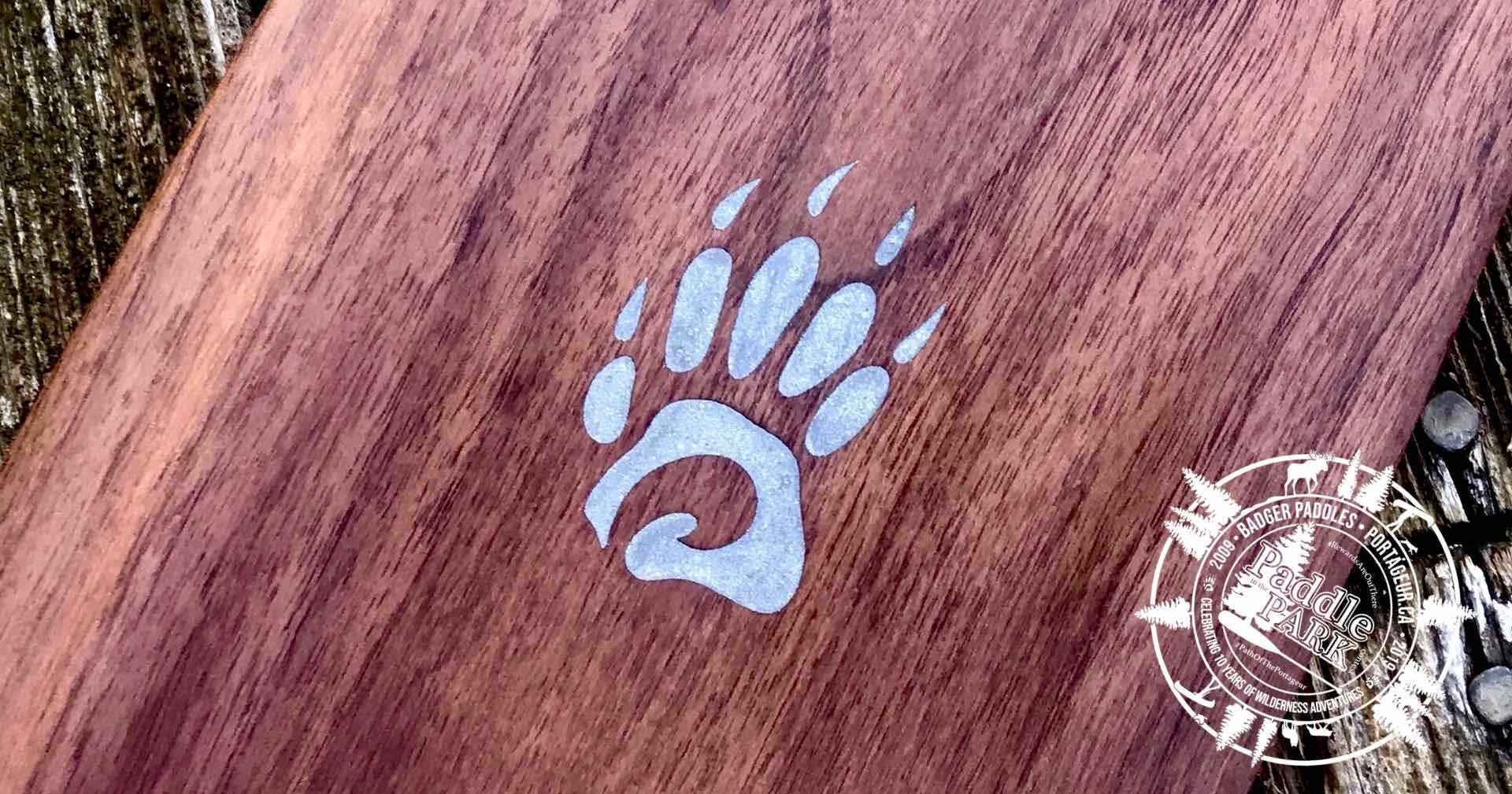 Special Edition Limited Issue Walnut Badger Canoe Paddle with laser engraved aluminum inlay Badger paw logo on rustic wood background