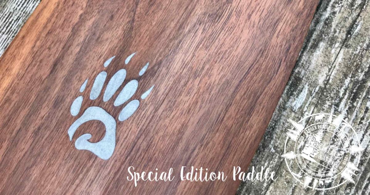 Special Edition Limited Issue Walnut Badger Canoe Paddle with laser engraved aluminum inlay Badger paw logo on rustic wood background