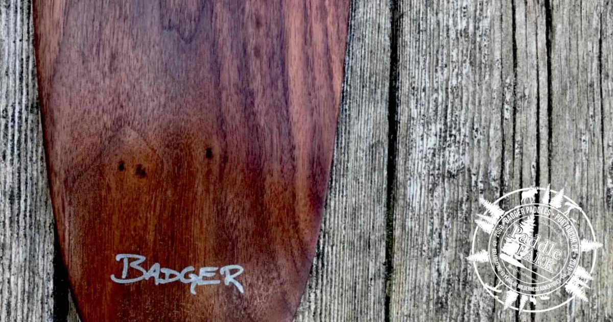 Special Edition Limited Issue Walnut Badger Canoe Paddle with laser engraved aluminum inlay Badger text logo on rustic wood background
